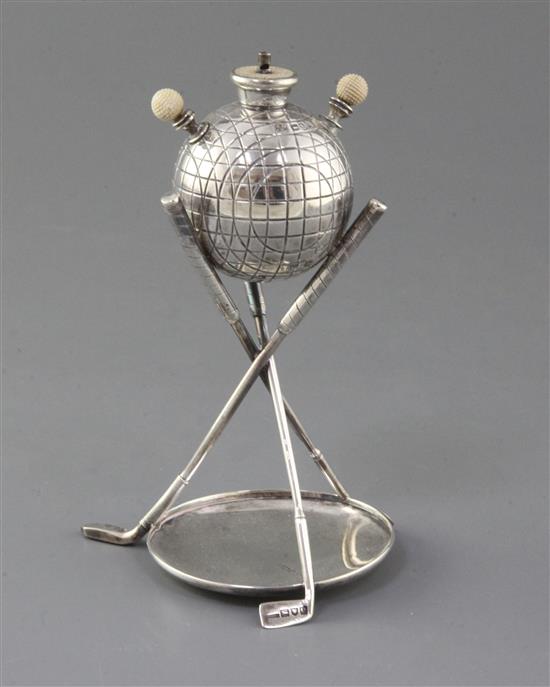 A late Victorian novelty silver and ivory mounted table club lighter, modelled as a golf ball above three crossed golf club supports.